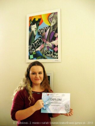 Dominika s ocenením a svojou prácou v pozadí